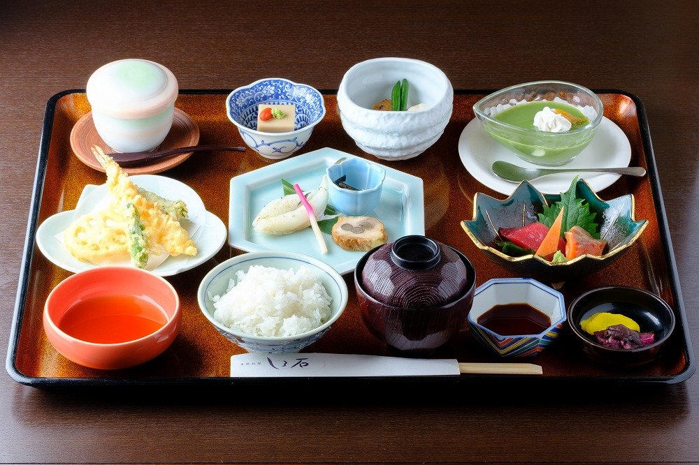 朱色の器に盛られた前菜と小鉢が並ぶ季節の懐石料理の近景